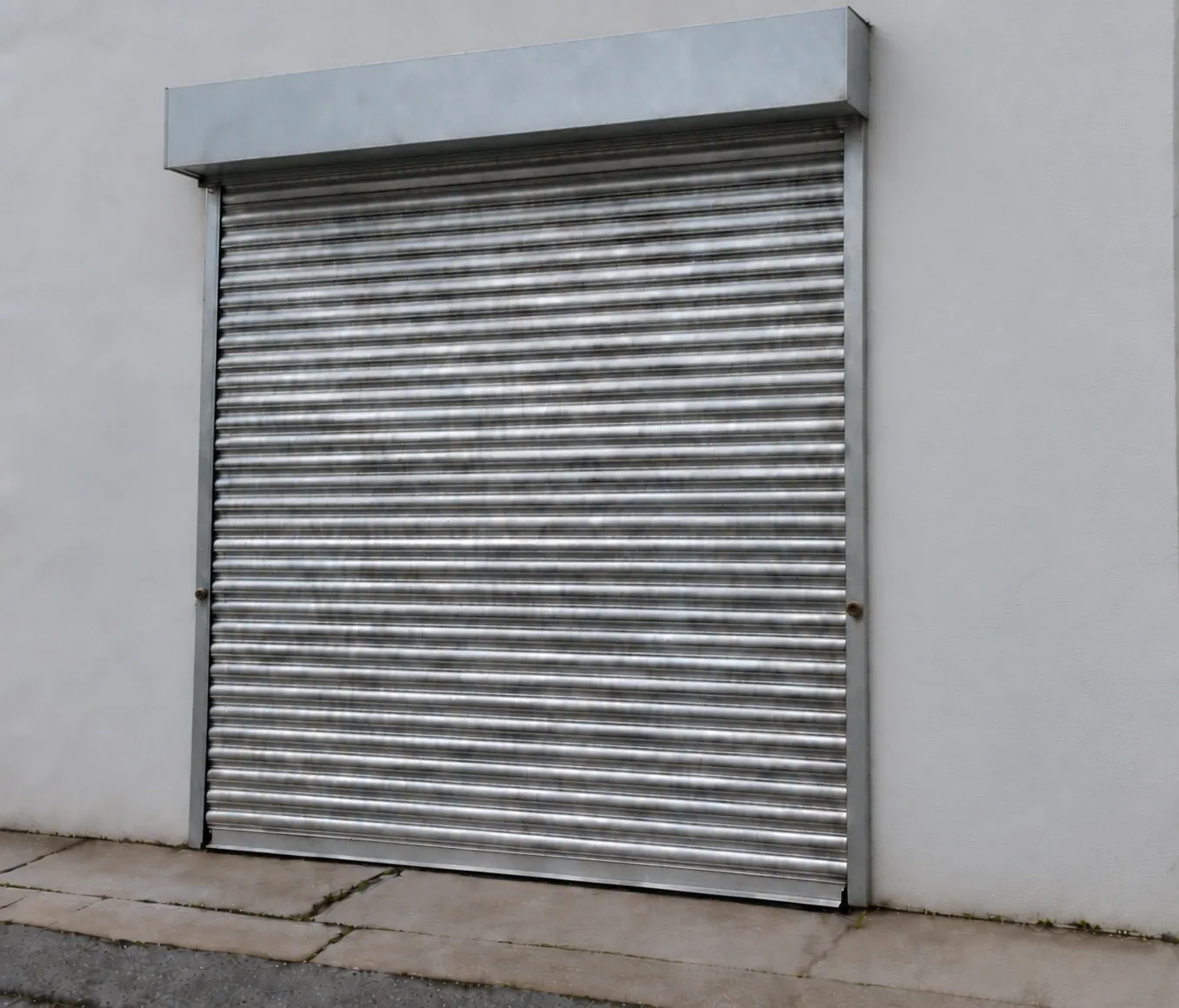 Outside the 150 sq ft unit: galvanised roller shutter in a white rendered wall