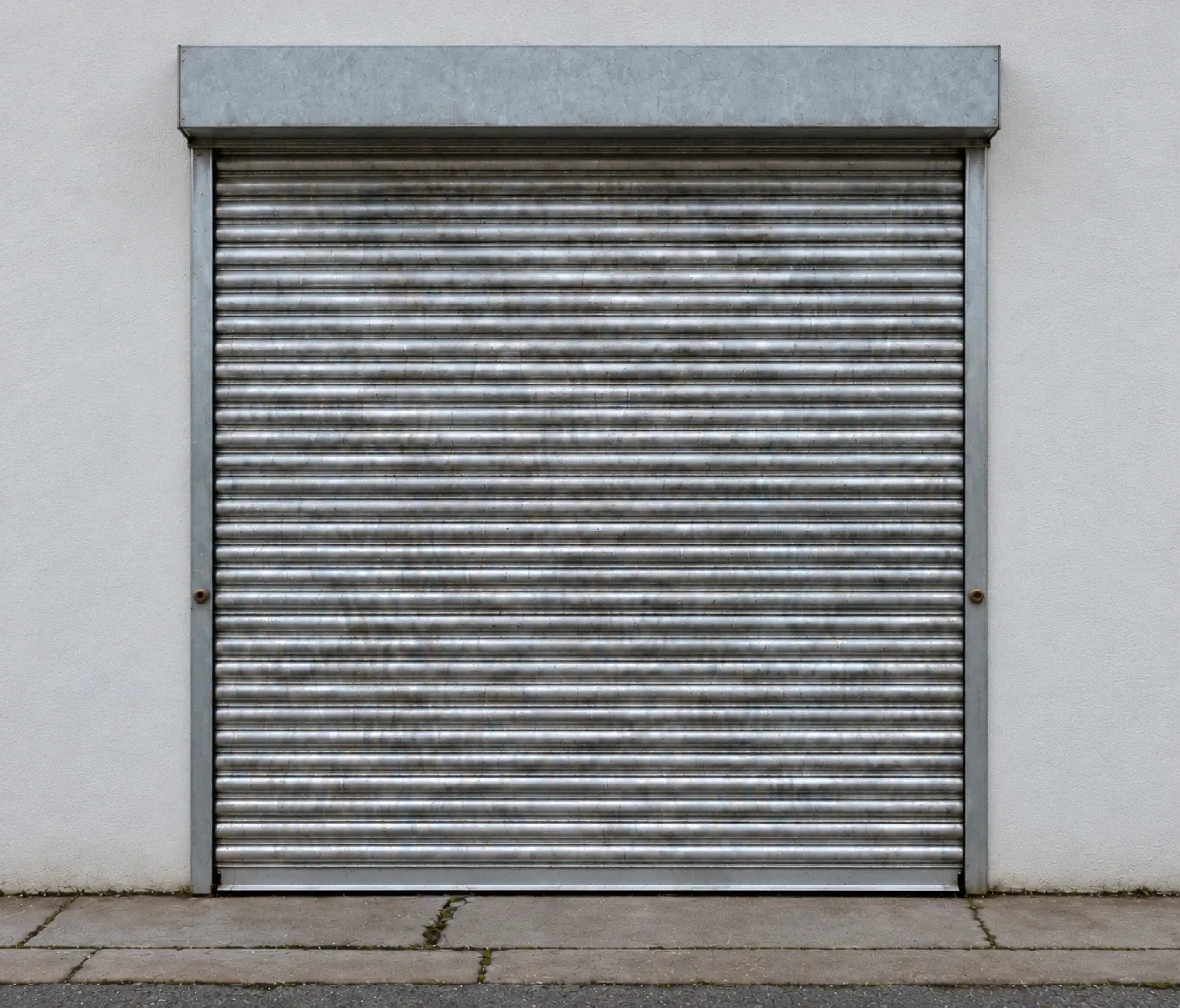 Outside the 180 sq ft unit: galvanised roller shutter in a white rendered wall